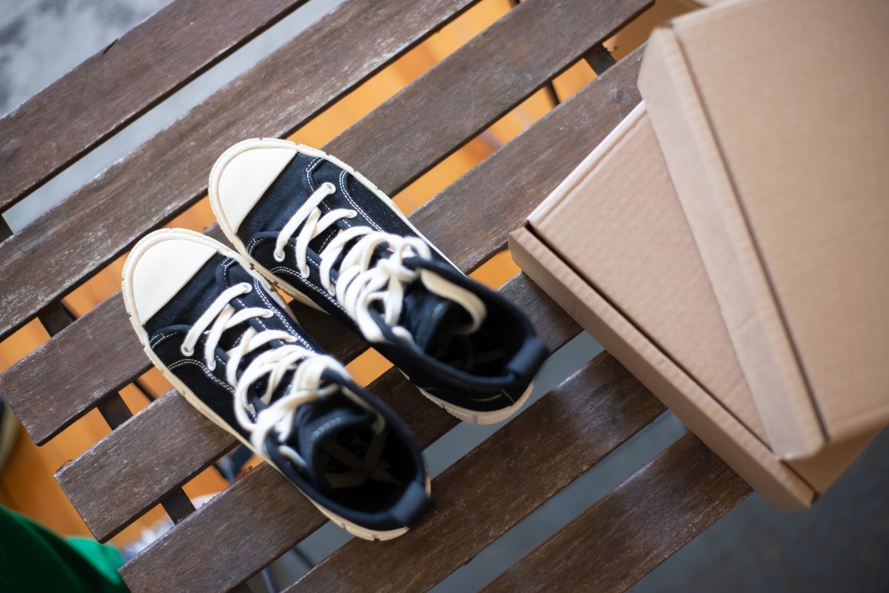 Stylish high top sneakers on a rustic wooden bench with cardboard boxes. Perfect for fashion shoots.